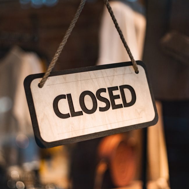 A close up of a closed sign hanging from a rope