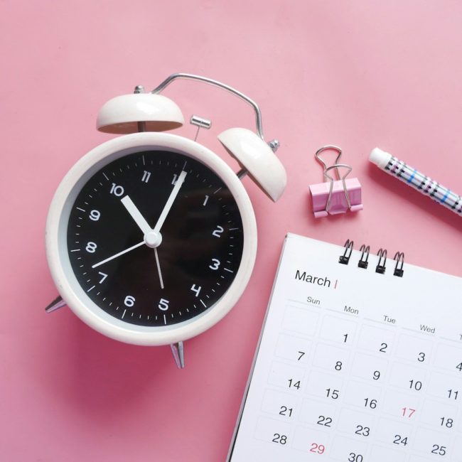 white and pink analog alarm clock